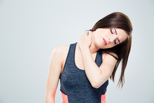 Fitness young woman with neck pain over gray background